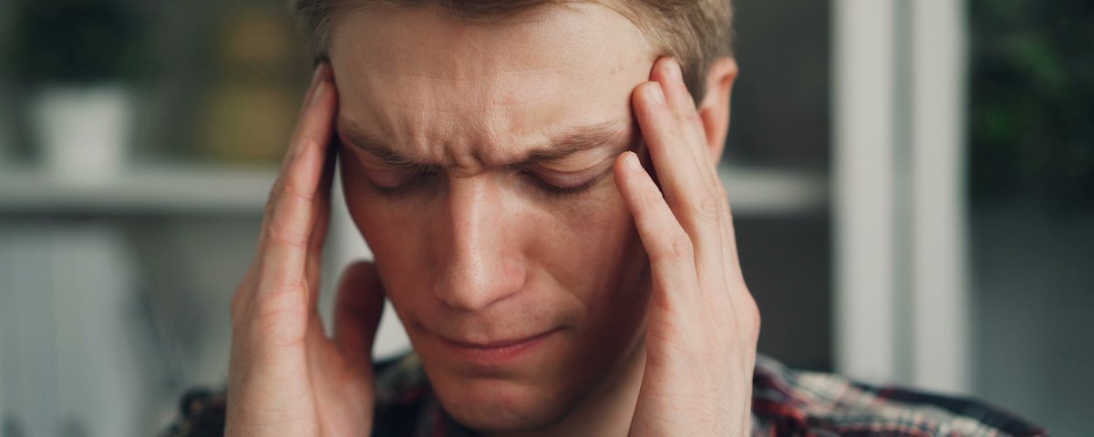 Uomo con gli occhi chiusi che si tiene le tempie